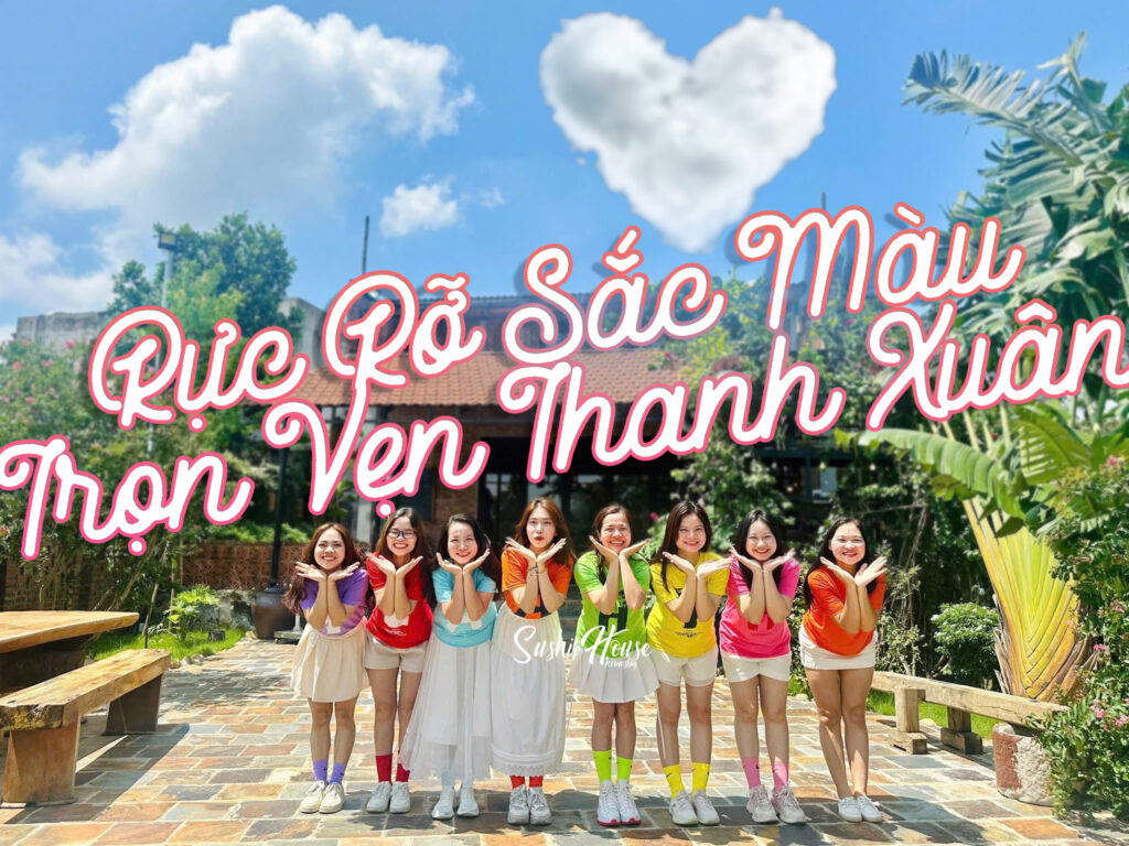 Nhóm bạn mặc trang phục nhiều màu sắc tạo dáng trước homestay ngoại ô Hà Nội có không gian xanh và mái ngói đỏ, nắng đẹp, phù hợp chụp ảnh thanh xuân.